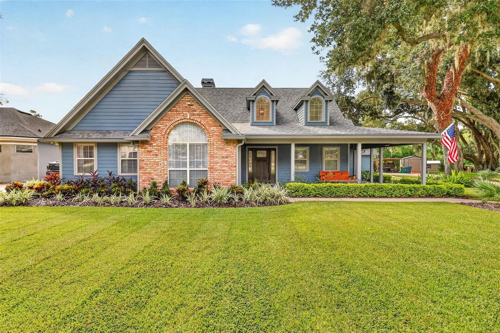 Front of house with brick accent and covered front porch. View of dormer windows from the exterior of home. - 267 RESERVE DR, TAVARES
