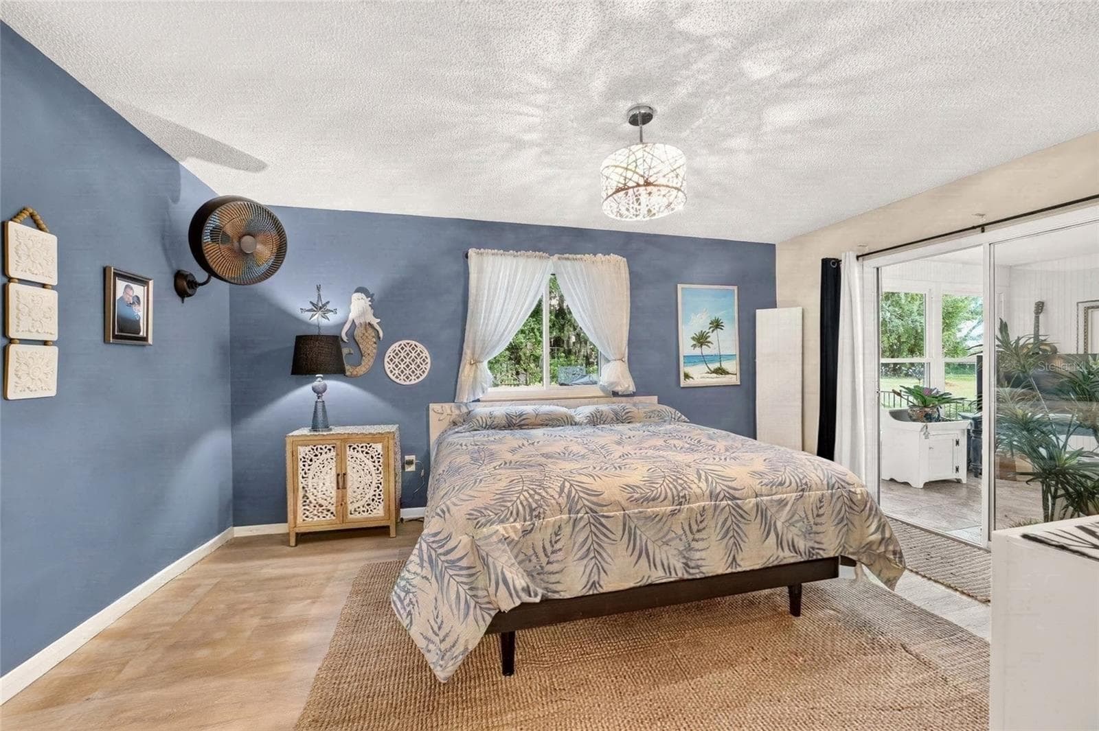 Primary Bedroom with direct access to the Florida room with sliders for light and curtains for privacy. Its the best of both worlds. Private Lot with lots of natural light. A pretty view from every room - 9282 SW 109TH LN, OCALA