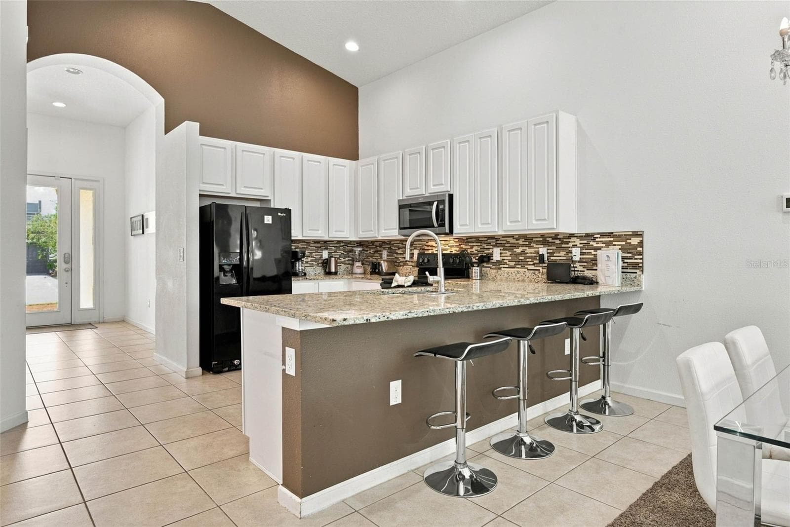 Open kitchen with 42" white cabinets, black Whirlpool appliances and granite countertops. - 337 MARCELLO BLVD, KISSIMMEE
