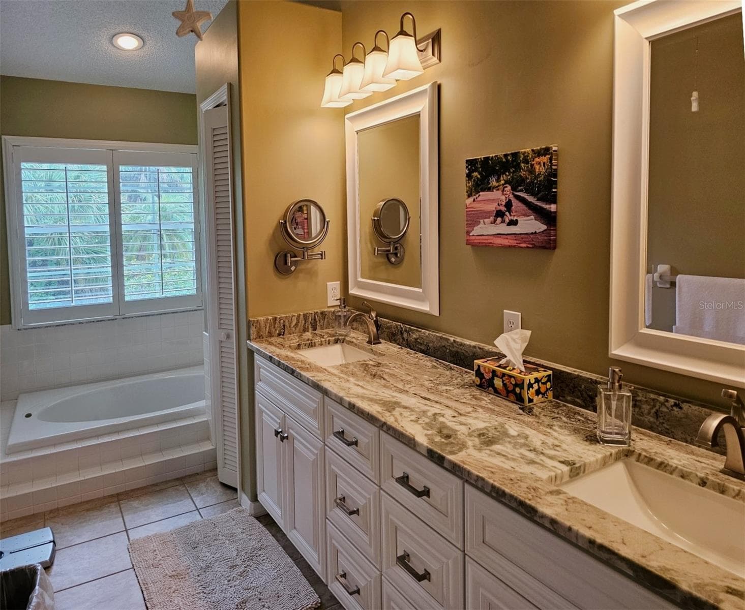 The primary bath features a soaking bathtub, dual vanieties, granite counters and a linen closet - 8351 CREEKVIEW LN, ENGLEWOOD