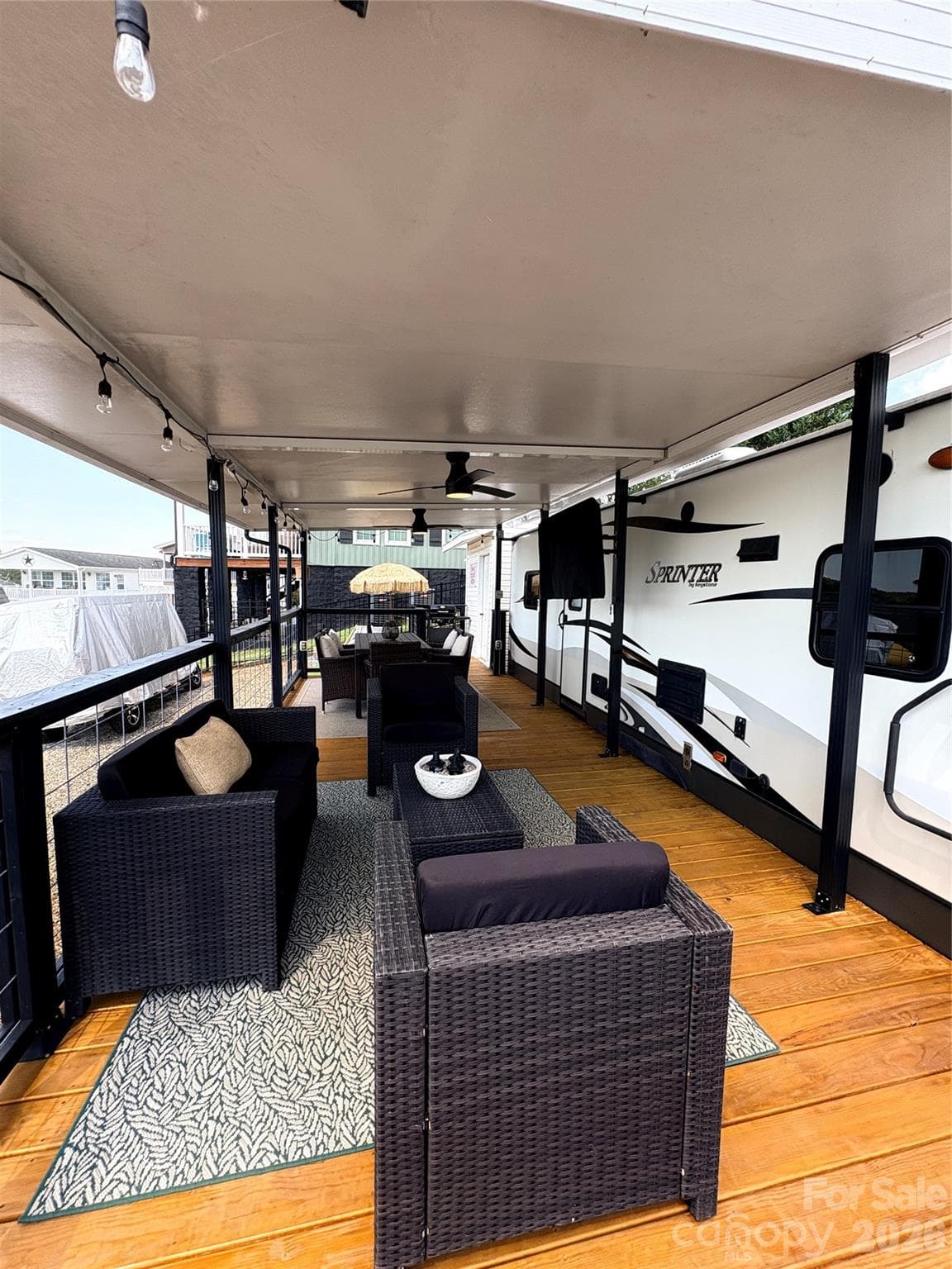 Covered Deck with String Lights, 2 Ceiling Fans, Dining and Lounging furniture and a mounted TV - 221 Grand View Drive, New London