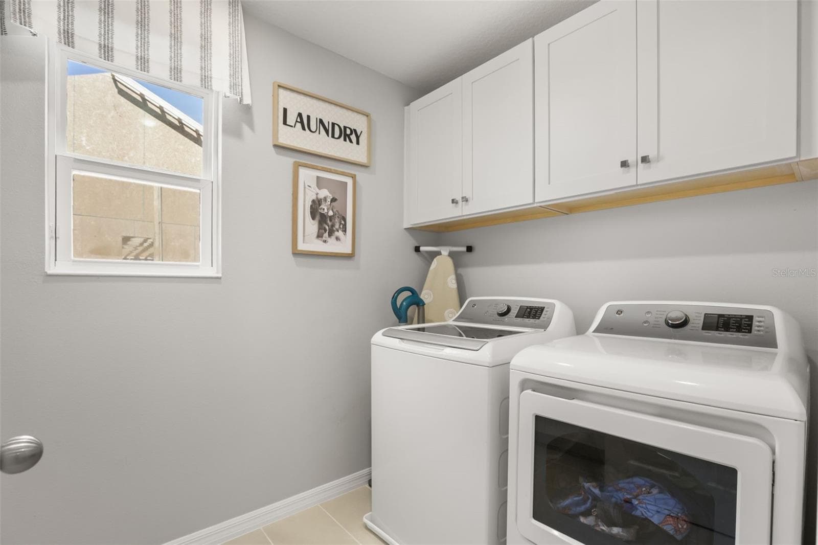 Laundry room with washer, dryer, upper cabinetry, and natural light. - 7104 DILLY LAKE AVE, GROVELAND