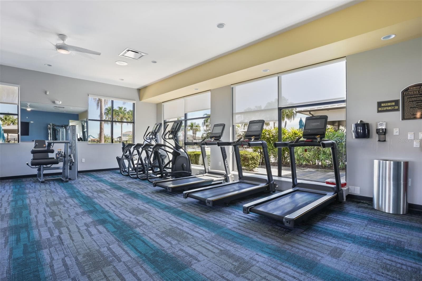 Another view of the Trinity Lakes fitness center with treadmills, cardio equipment, and natural light. - 7104 DILLY LAKE AVE, GROVELAND