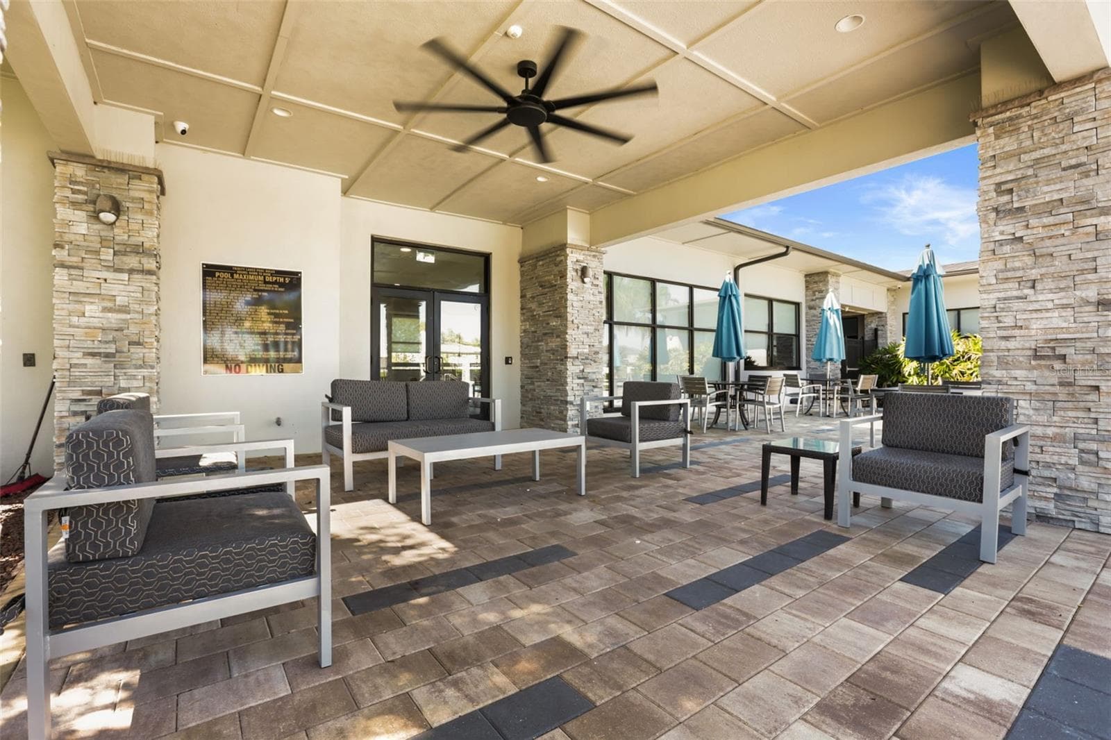 Covered outdoor lounge area at the Trinity Lakes clubhouse with plenty of seating. - 7104 DILLY LAKE AVE, GROVELAND