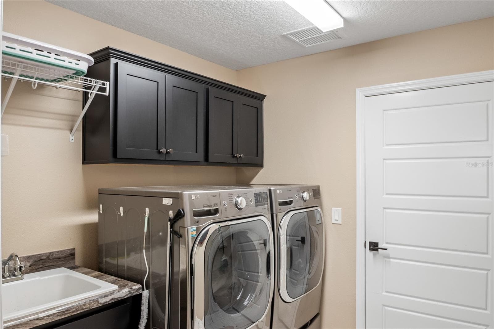 Interior laundry with sink.  Dryer is set up for gas or electric connection.  Extra Storage above washer and dryer. - 4529 SAMANTHA CT, THE VILLAGES