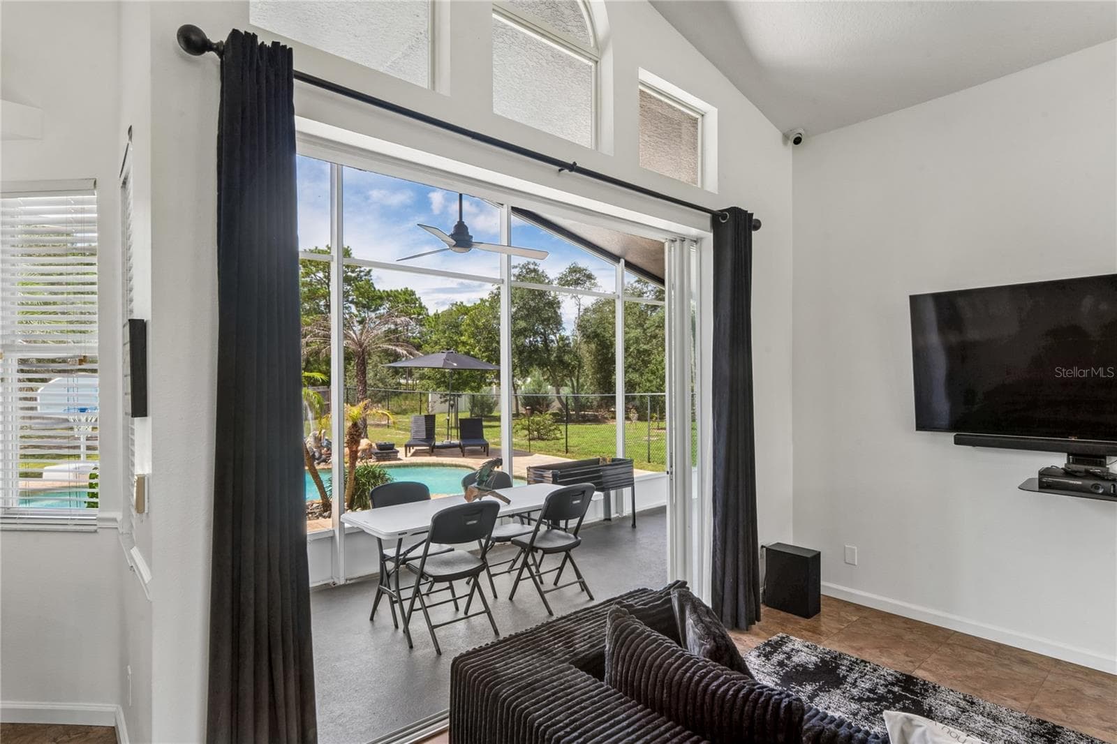 Living Room looking onto screened lanai - sliders pocket into wall - 11309 LAPWING RD, WEEKI WACHEE
