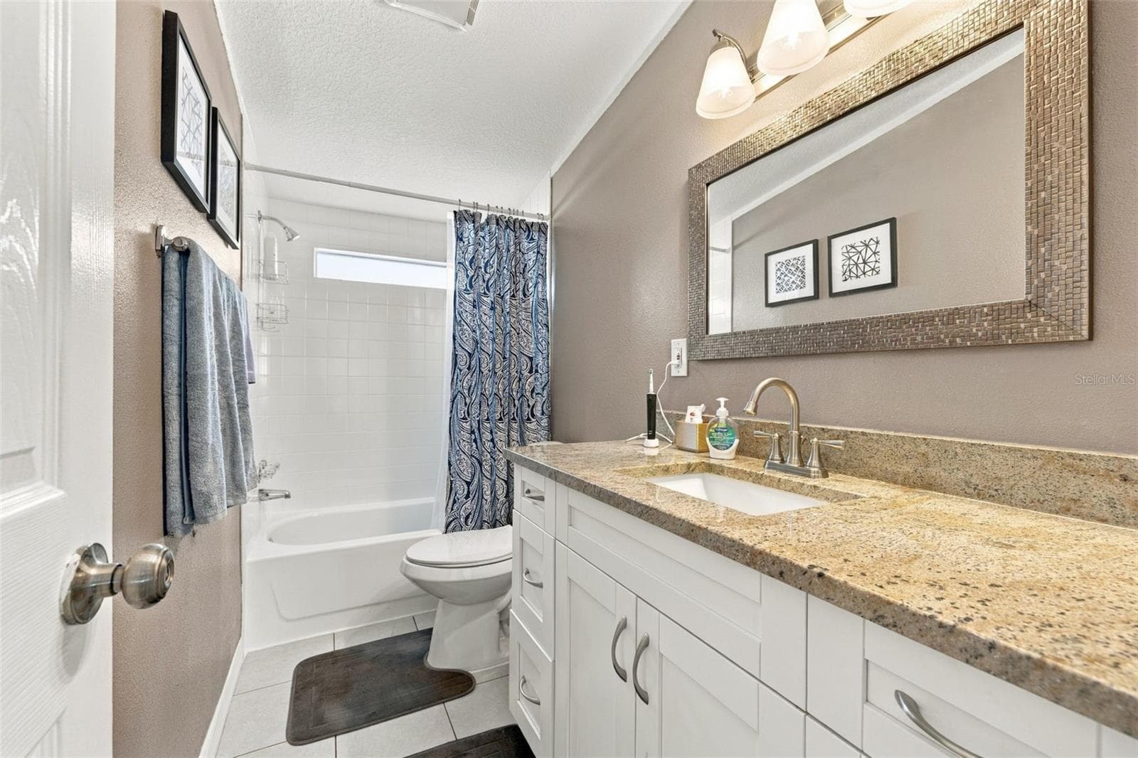 Secondary bathroom with shower/tub combo, updated vanity with high quality granite, updated fixtures, lighting and designer vanity mirror. - 3041 SHORT LEAF ST, WESLEY CHAPEL