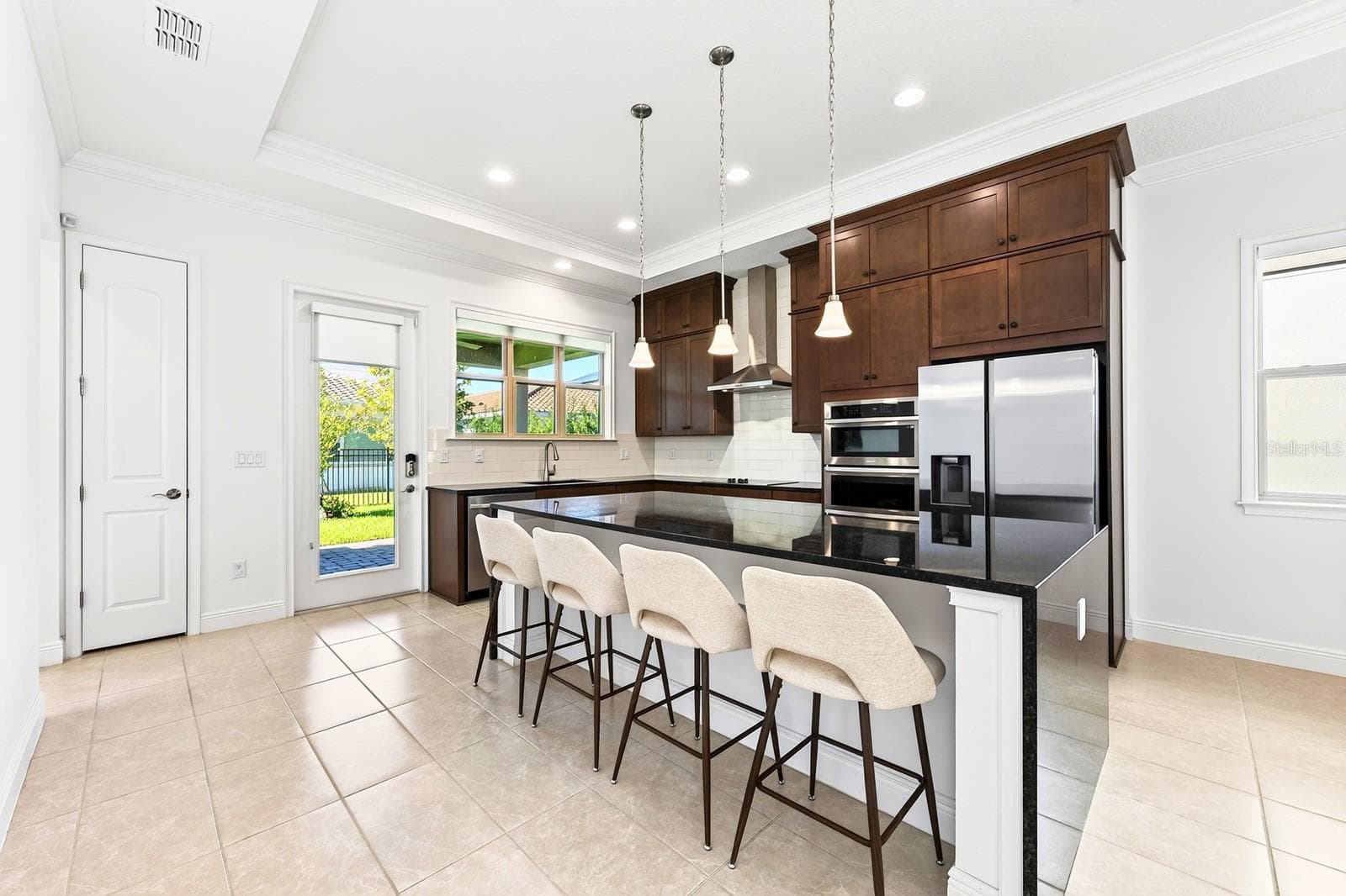 Beautifully appointed CHEF’S KITCHEN featuring rich SHAKER-STYLE CABINETRY, STAINLESS STEEL APPLIANCES, subway tile backsplash, pantry and a large WATERFALL ISLAND with breakfast bar seating. - 13472 PADSTOW PL, ORLANDO