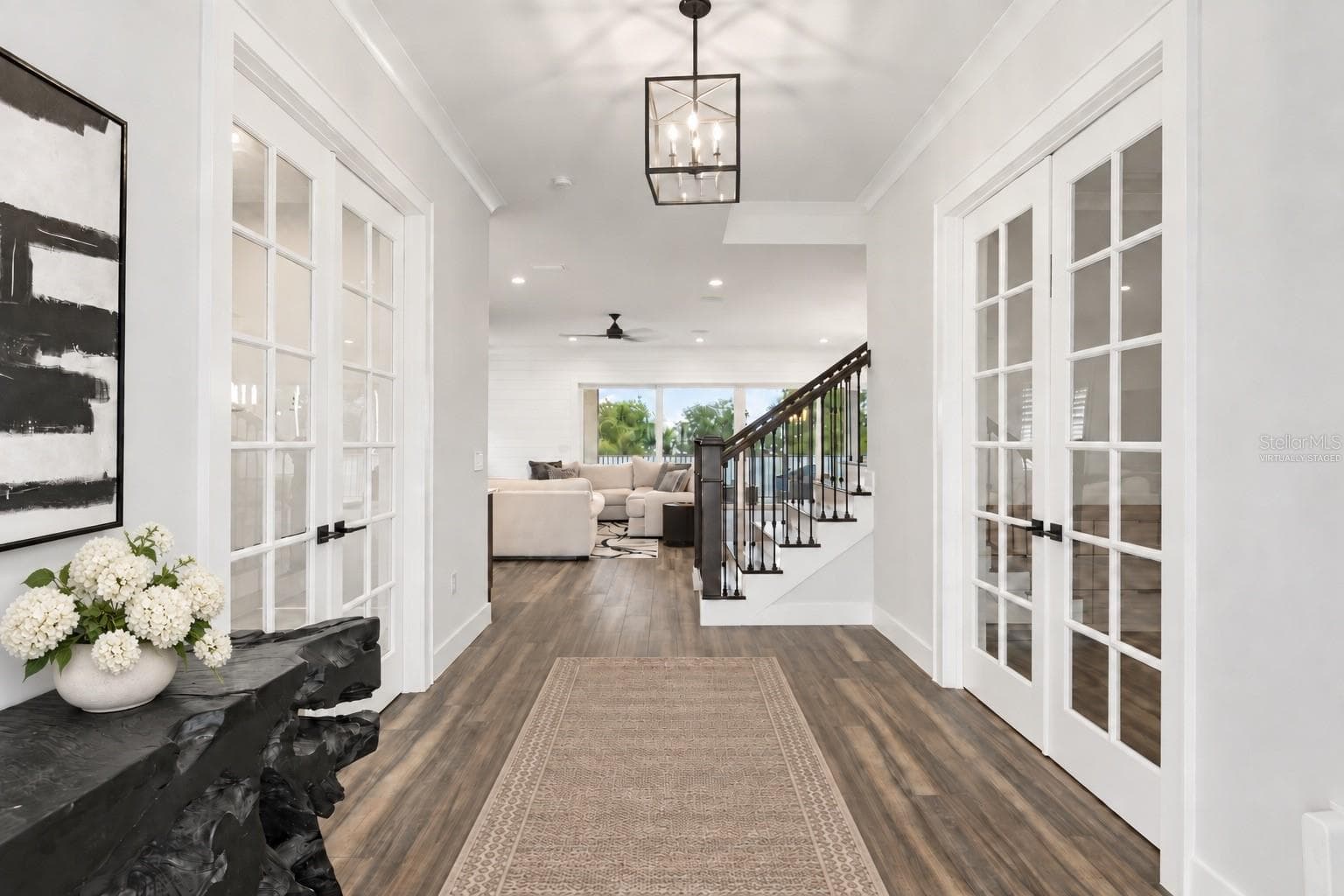 FOYER | HOME OFFICE + EN SUITE FLEX ROOM French doors off the foyer lead to a dedicated home office on one side and an en suite guest, au pair or second office space on the other.Virtually Staged — runner and floral arrangement added - 907 CELADON ST, WINTER GARDEN