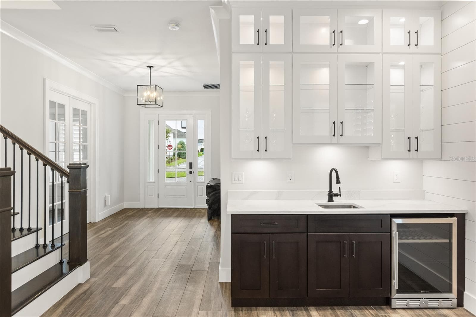 BUILT-IN WET BARA built-in wet bar with sink, beverage refrigerator and glass-front cabinetry sits just off the foyer, opening to the main living area for easy entertaining. - 907 CELADON ST, WINTER GARDEN