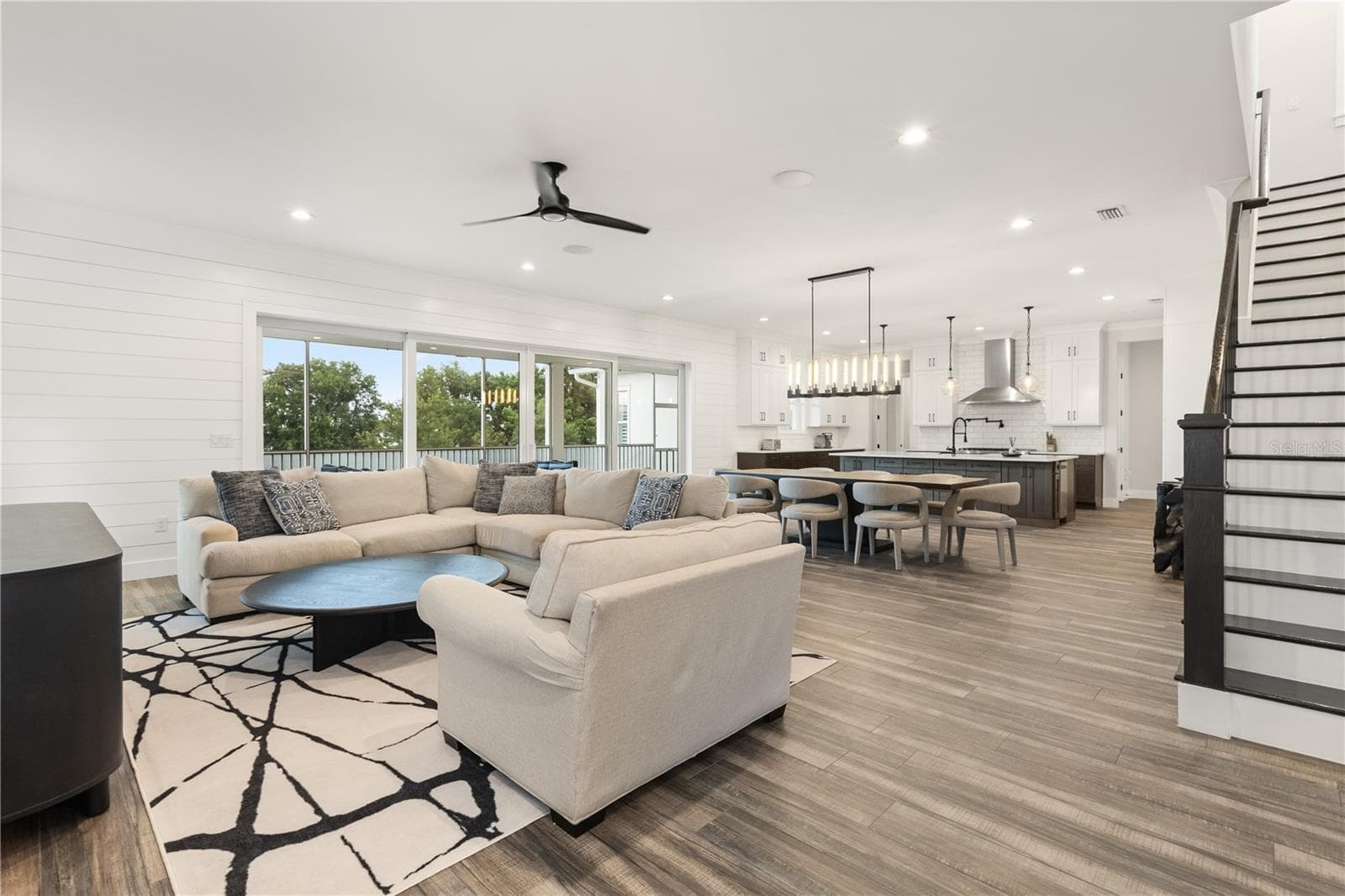 LIVE, DINE, SOCIAL Extends toward the kitchen and expansive sliding glass doors, bringing the screened porch and conservation landscape into view. - 907 CELADON ST, WINTER GARDEN