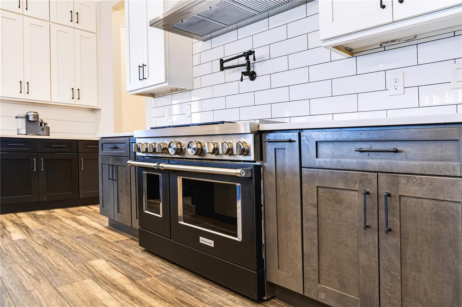PROFESSIONAL-STYLE COOKING | KITCHEN AID OVENSA substantial range, vent hood and pot filler create a dedicated cooking zone surrounded by generous counter space and cabinetry. - 907 CELADON ST, WINTER GARDEN