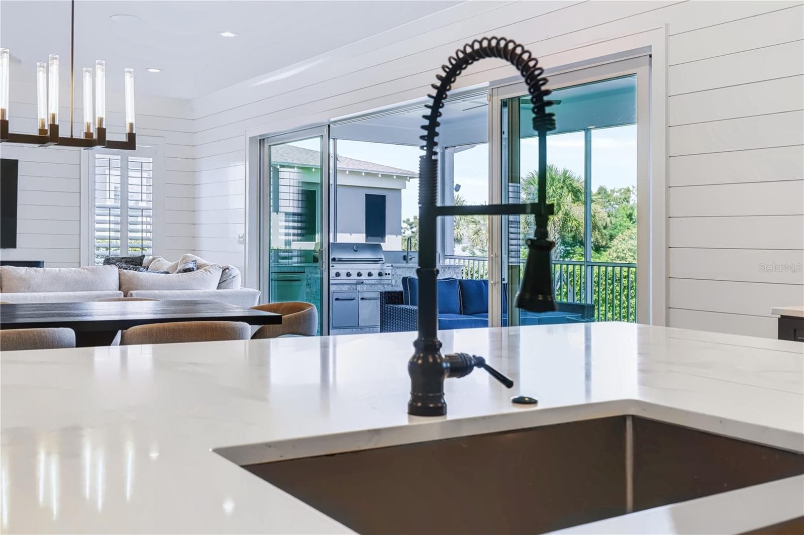 INDOOR-OUTDOOR LIVINGFrom the kitchen island, the open living and dining spaces lead directly through expansive sliding glass doors to the screened porch and outdoor kitchen. - 907 CELADON ST, WINTER GARDEN