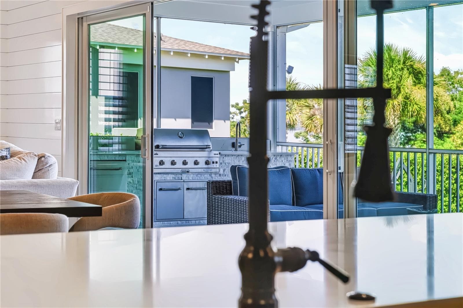 KITCHEN TO OUTDOOR KITCHENThe kitchen’s oversized island sits within direct sight of the screened porch and outdoor kitchen, creating an easy connection between indoor cooking and outdoor entertaining. - 907 CELADON ST, WINTER GARDEN