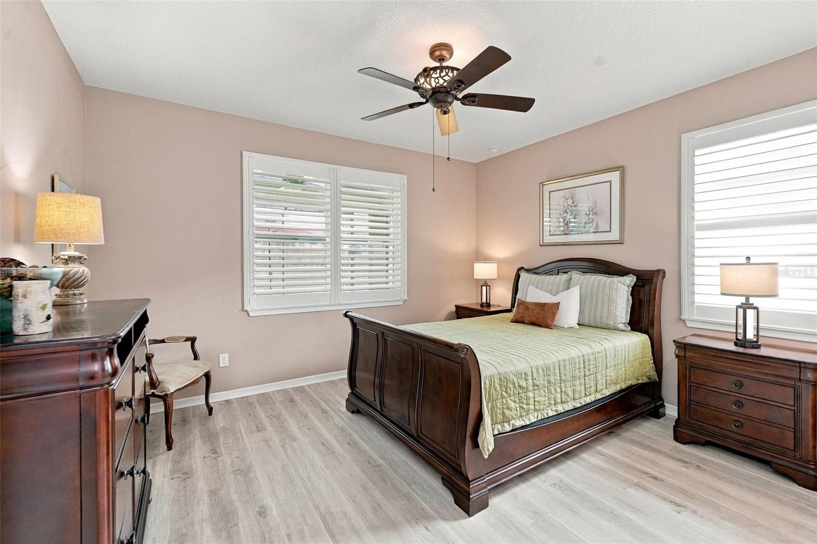 Primary Bdrm w/luxury vinyl plank floors, ceiling fan, & windows w/plantation shutters - 5995 SW 93RD CIR, OCALA