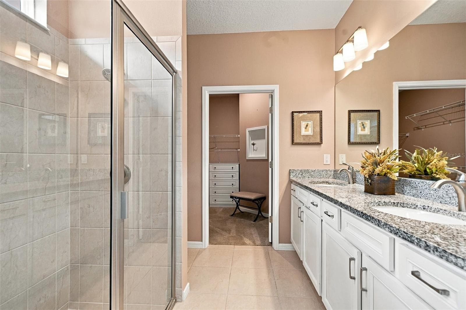 Primary en-suite bath w/walk-in tiled shower, built-in bench, transom window, granite countertop, dual vanity & closet w/laundry chute door - 5995 SW 93RD CIR, OCALA