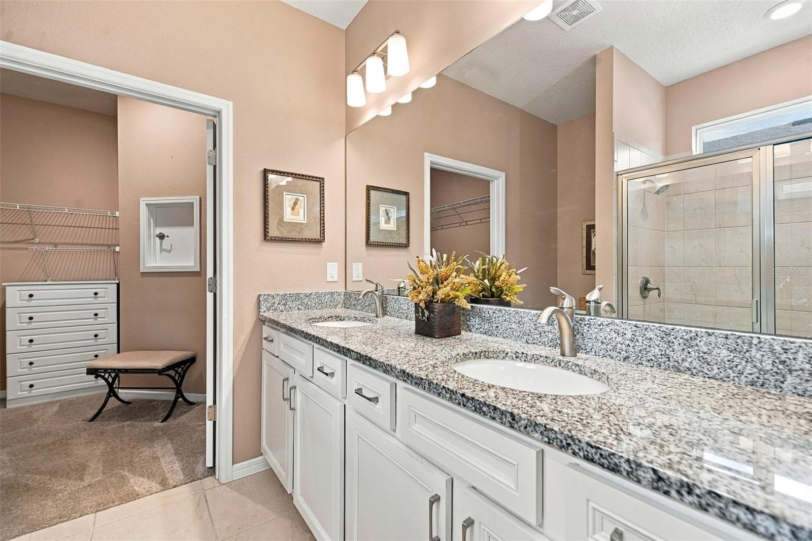 Primary en-suite bath w/walk-in tiled shower, built-in bench, transom window, granite countertop, dual vanity & closet w/laundry chute door - 5995 SW 93RD CIR, OCALA