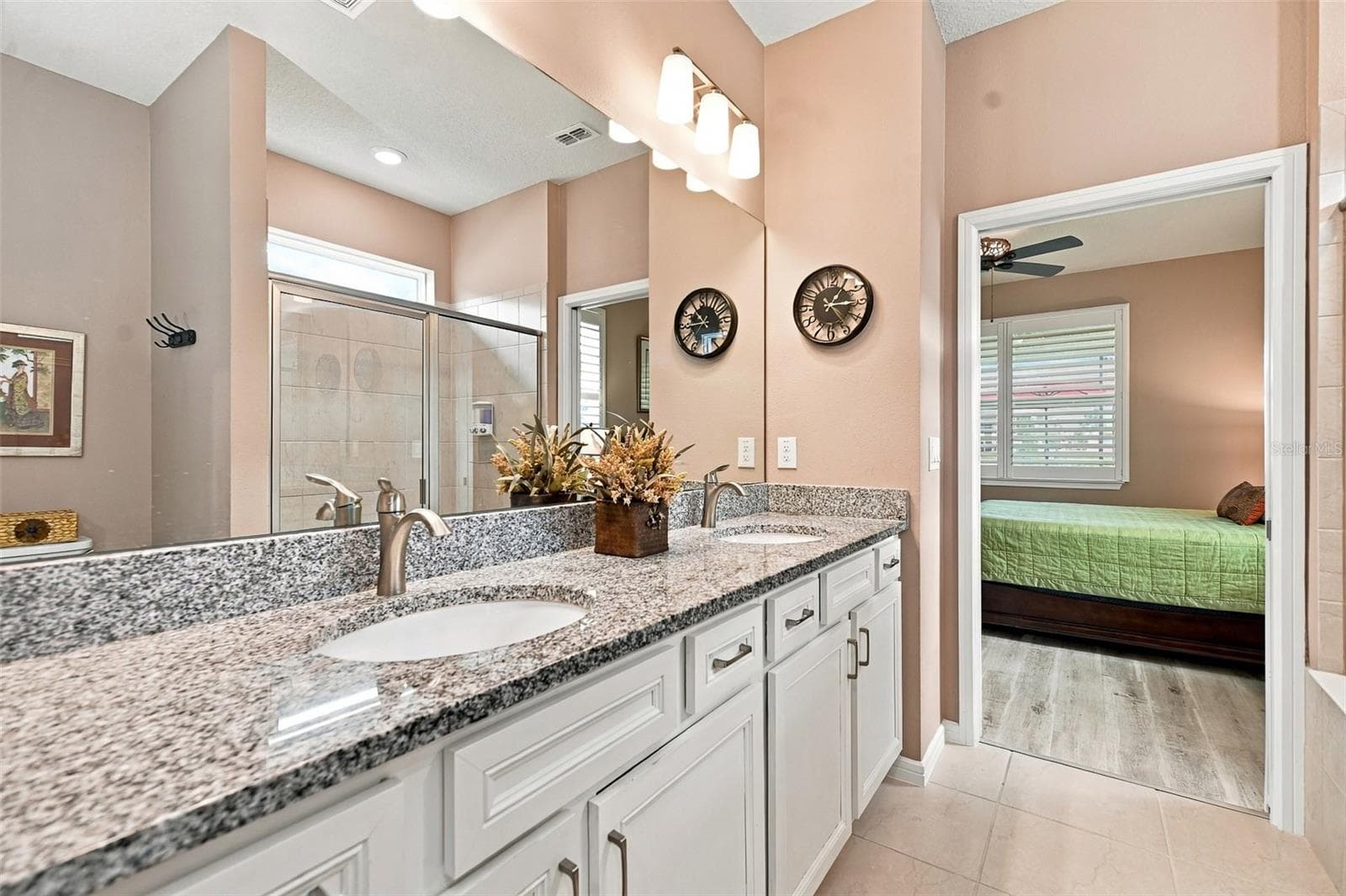 Primary en-suite bath w/walk-in tiled shower, built-in bench, transom window, granite countertop, dual vanity & closet w/laundry chute door - 5995 SW 93RD CIR, OCALA