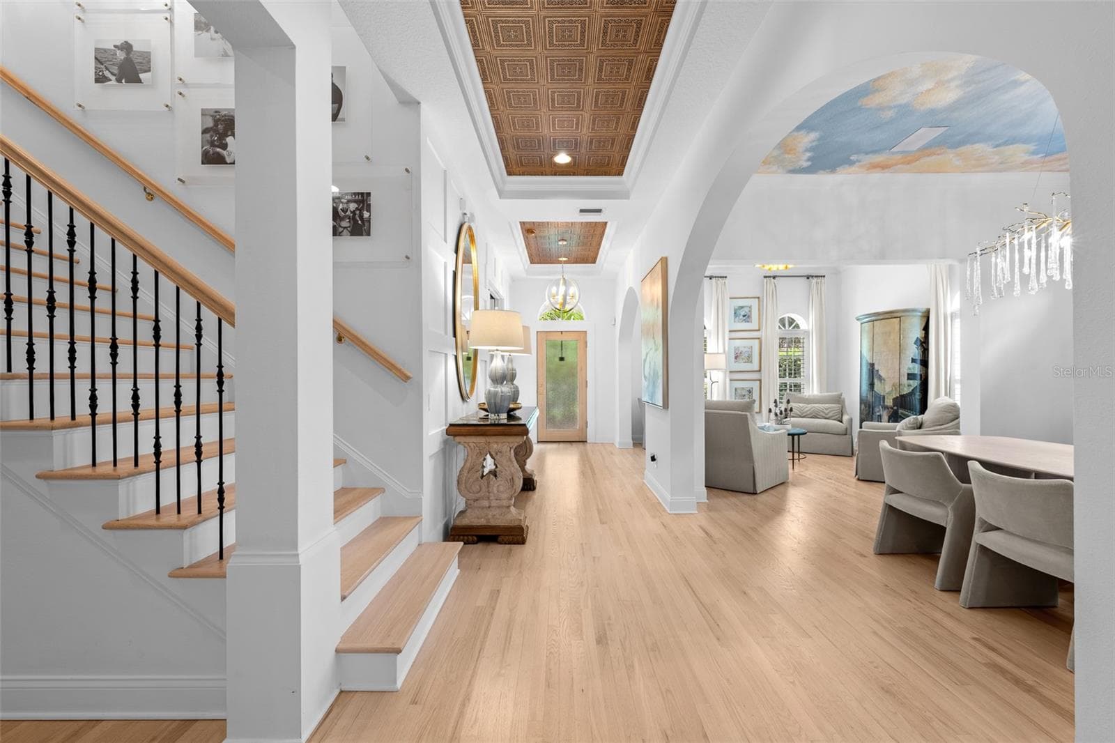 Foyer with light wood flooring, wood-inlay ceiling detail, staircase with iron balusters, and arched openings to the living spaces. - 1921 FLORESTA VIEW DR, TAMPA