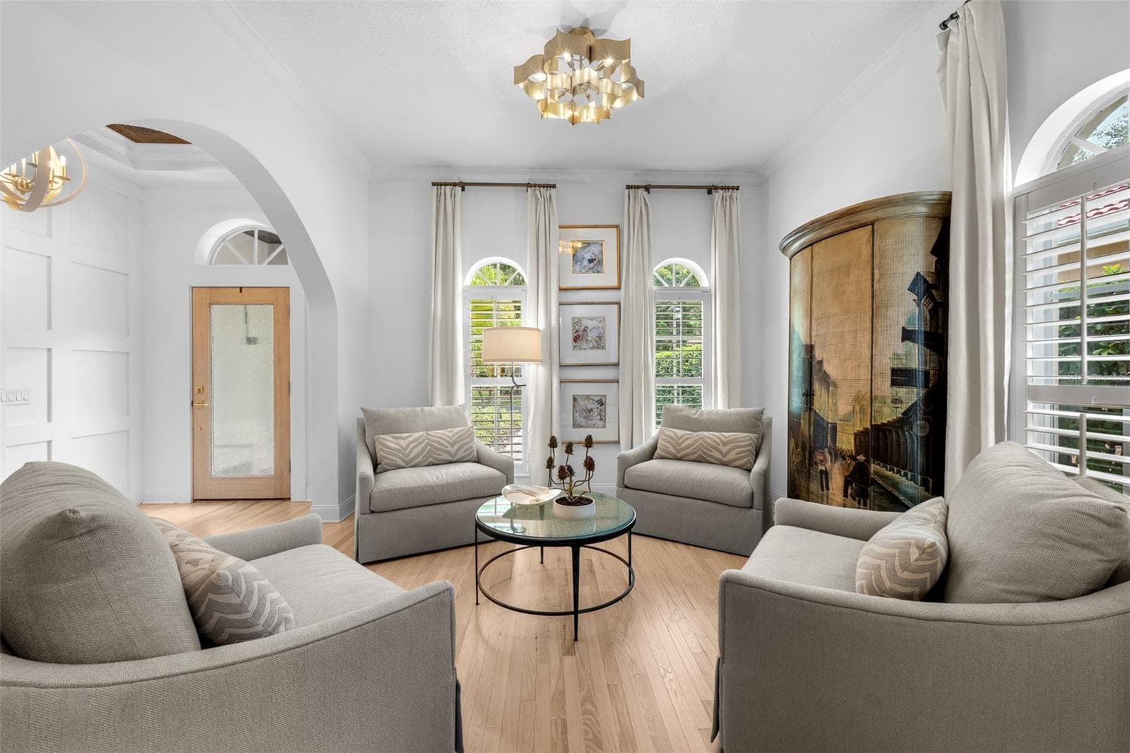 Sitting area with arched windows, plantation shutters, crown molding, and a crystal-style pendant fixture. - 1921 FLORESTA VIEW DR, TAMPA