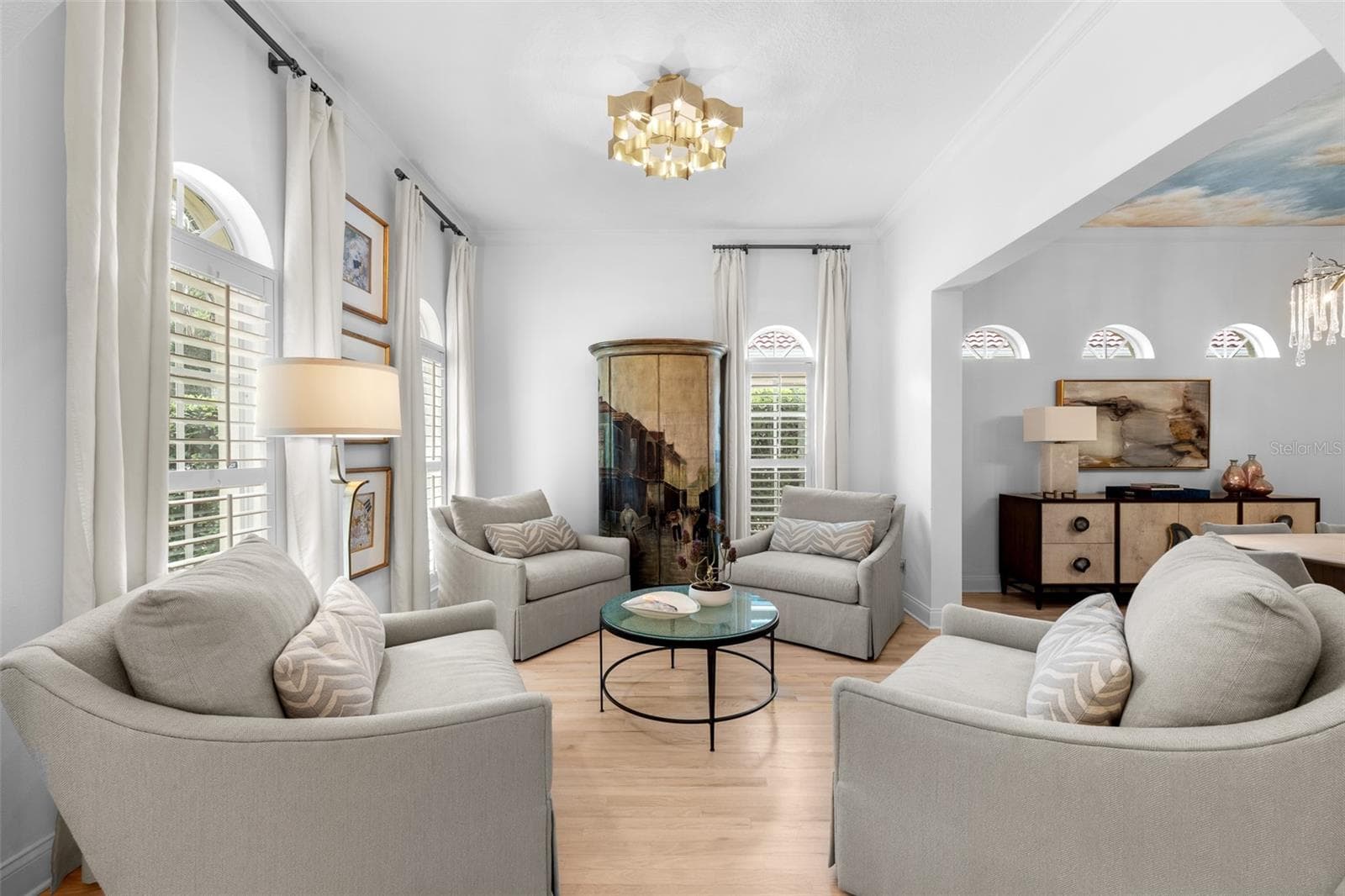 Light wood flooring, twin arched windows, and an open view into the adjoining dining room. - 1921 FLORESTA VIEW DR, TAMPA