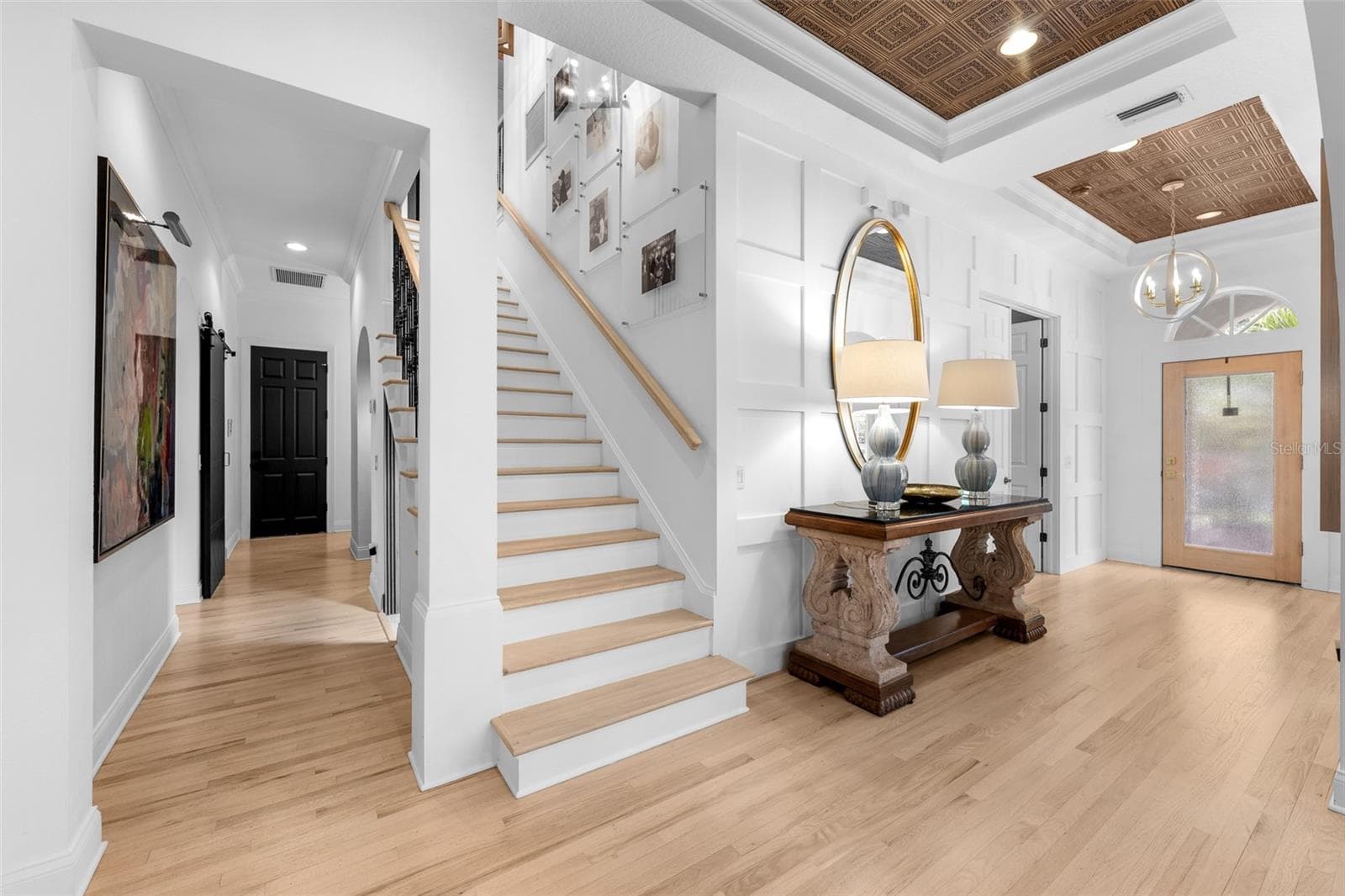 Wood-tread stairs with iron spindles, wall paneling, and a wood-inlay tray ceiling above the entry. - 1921 FLORESTA VIEW DR, TAMPA