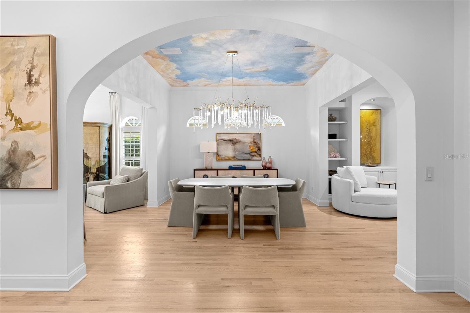 View through the arched entry to the dining room, showing the mural ceiling and chandelier. - 1921 FLORESTA VIEW DR, TAMPA