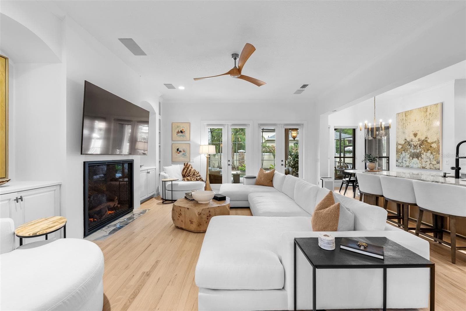 Fireplace with mounted TV above, built-in shelving, and French doors to the pool area. - 1921 FLORESTA VIEW DR, TAMPA