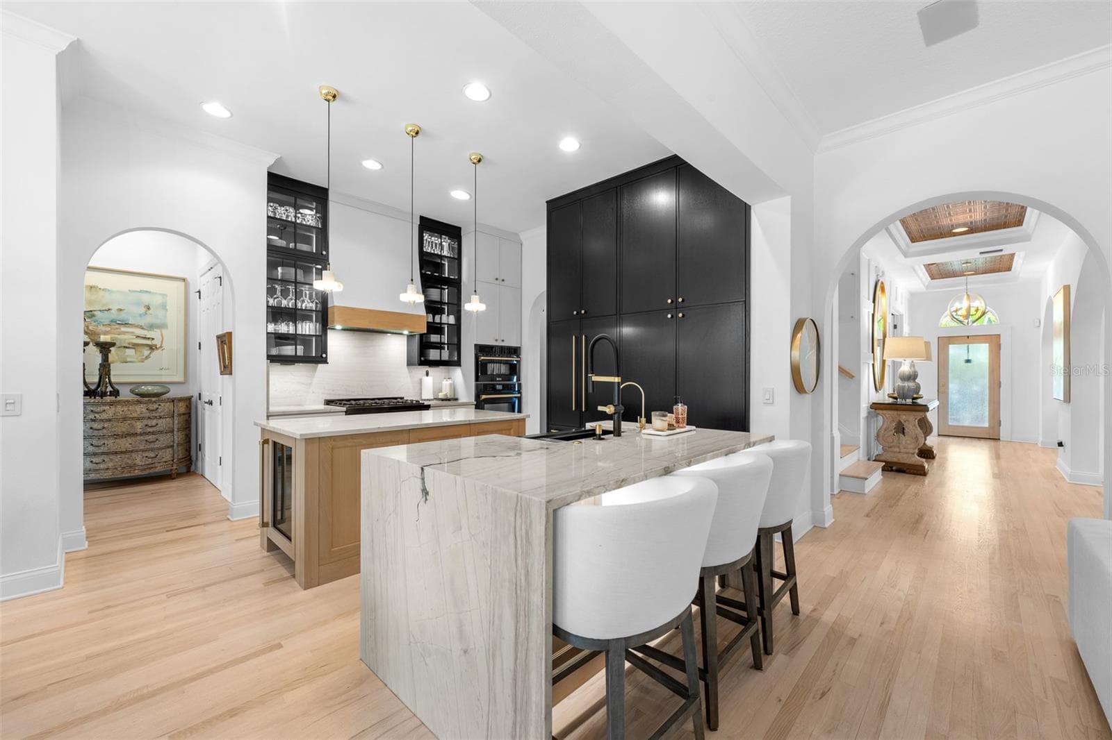 Two-tone cabinetry, waterfall-edge stone island with bar seating, pendant lighting, and arched openings to the foyer. - 1921 FLORESTA VIEW DR, TAMPA