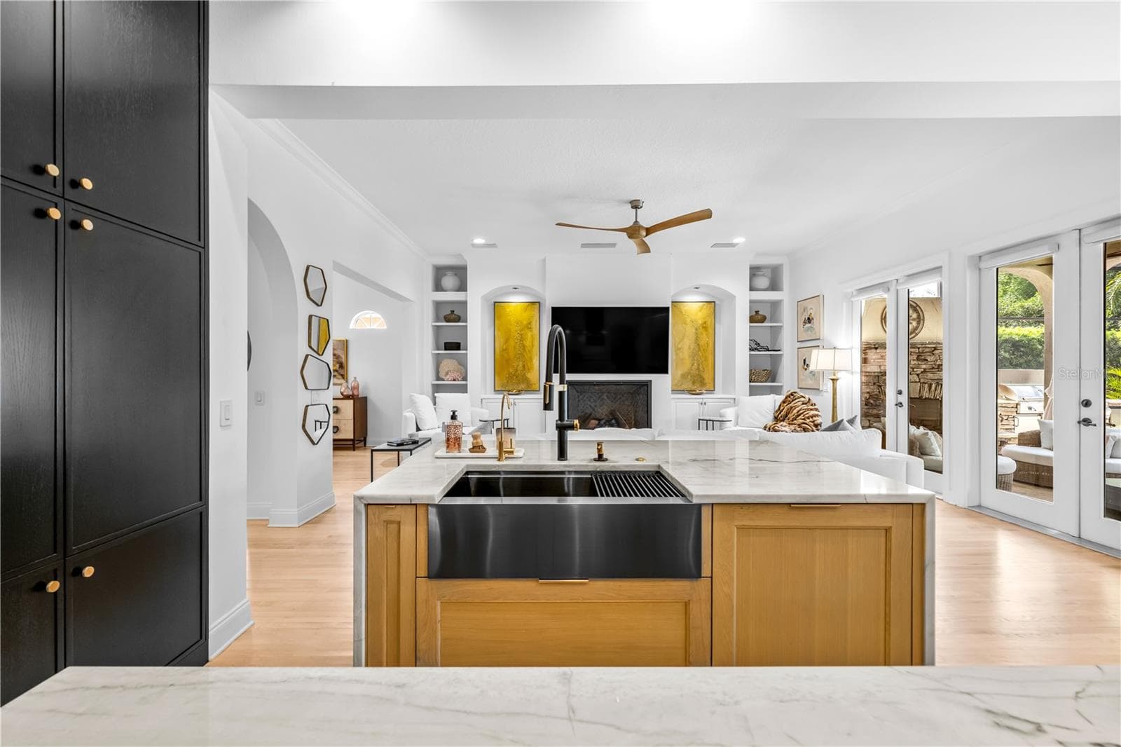 Farmhouse apron sink in a wood-front island, black tall cabinetry, and open sightline to the family room. - 1921 FLORESTA VIEW DR, TAMPA