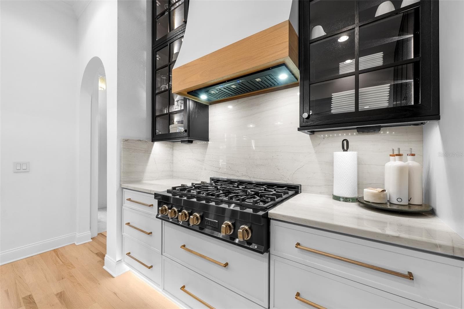 Six-burner gas cooktop, white tile backsplash, brass cabinet pulls, and stone countertops. - 1921 FLORESTA VIEW DR, TAMPA