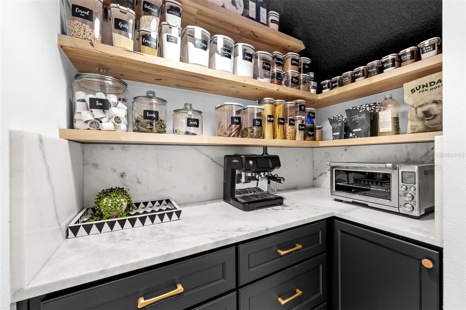 Floating wood shelving, stone counters, and black lower cabinets with brass hardware. - 1921 FLORESTA VIEW DR, TAMPA