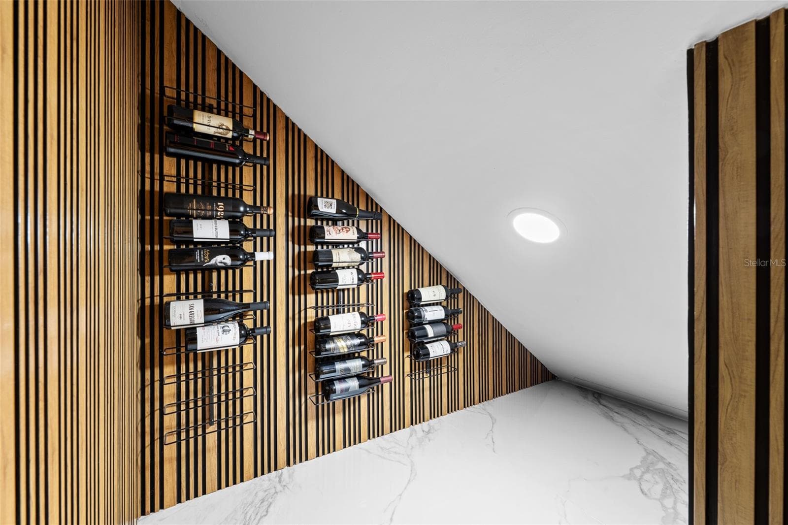 Wall-mounted wine racks on a vertical wood slat wall with recessed lighting. - 1921 FLORESTA VIEW DR, TAMPA