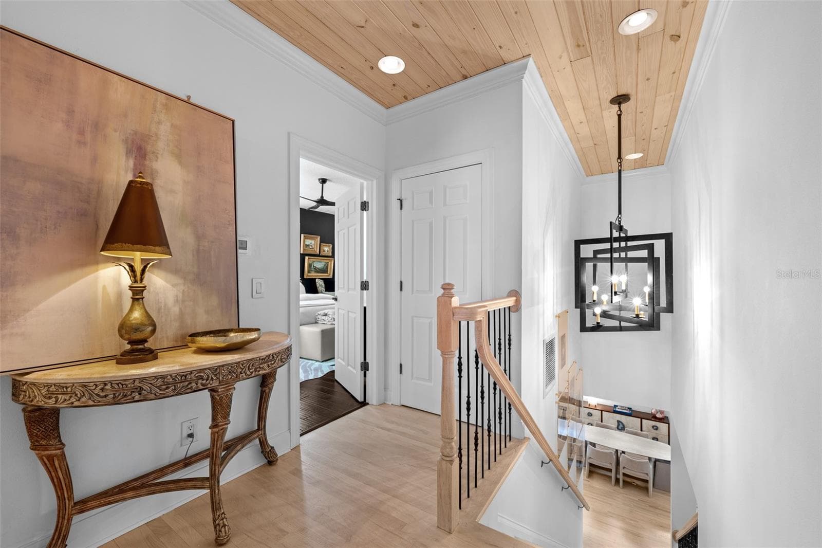 Upstairs landing — Vaulted wood plank ceiling, light wood flooring, and stair railing with lantern-style pendant. - 1921 FLORESTA VIEW DR, TAMPA