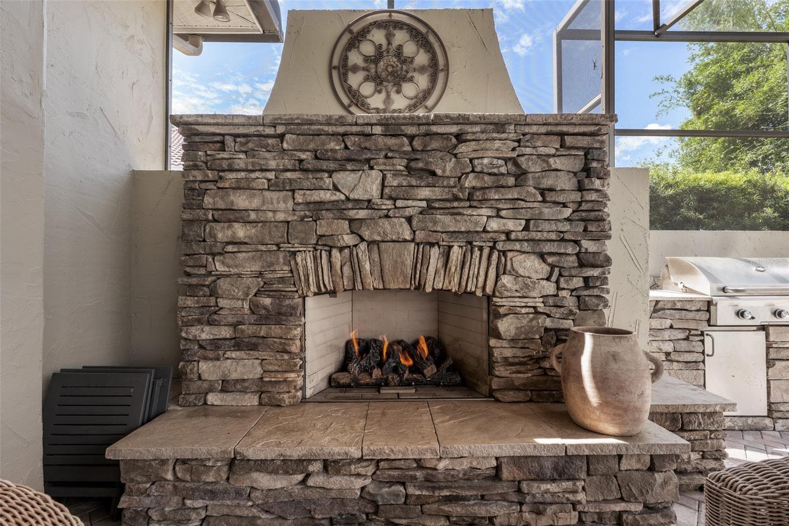Outdoor fireplace — Stacked-stone wood-burning fireplace with raised hearth on the lanai. - 1921 FLORESTA VIEW DR, TAMPA