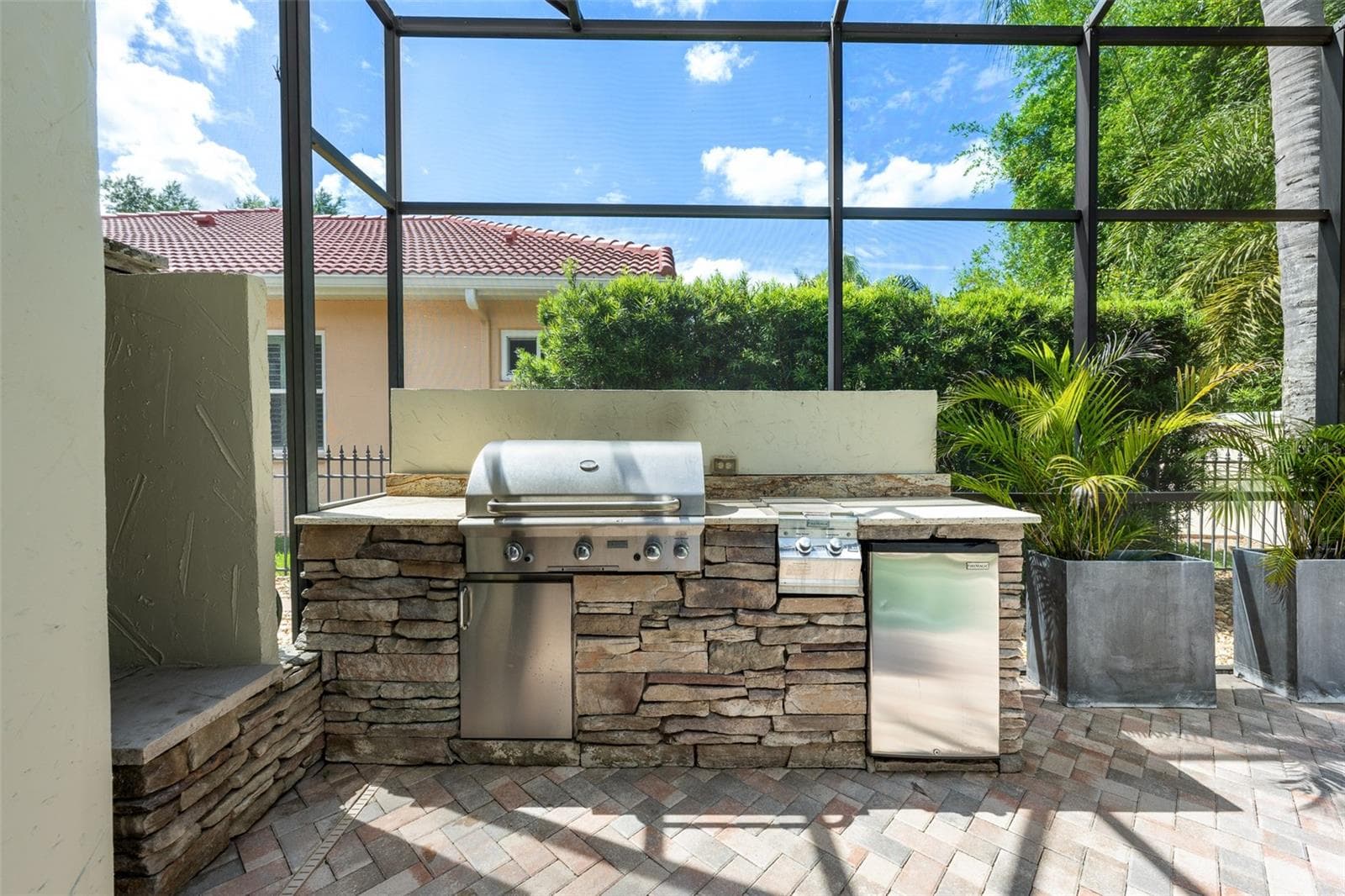 Outdoor kitchen — Stacked-stone outdoor kitchen with built-in gas grill and refrigerator. - 1921 FLORESTA VIEW DR, TAMPA