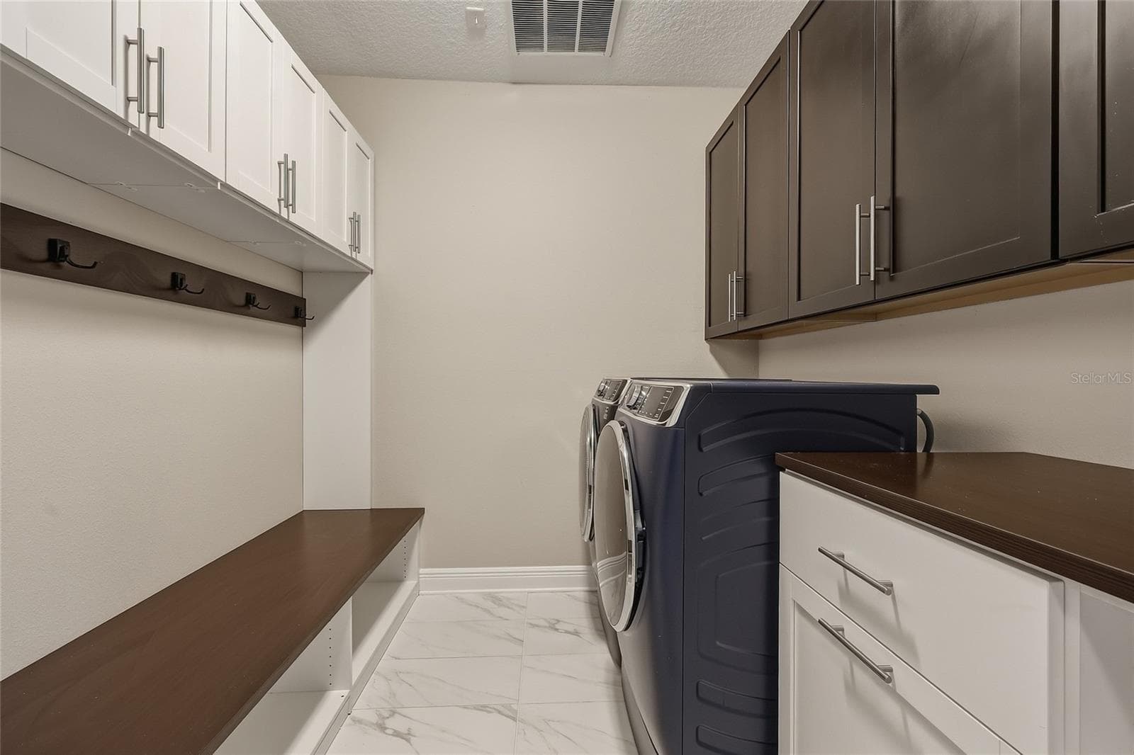 First floor laundry room with built-in cabinetry, bench, laundry hampers and drawers. - 10702 PLEASANT KNOLL DR, TAMPA