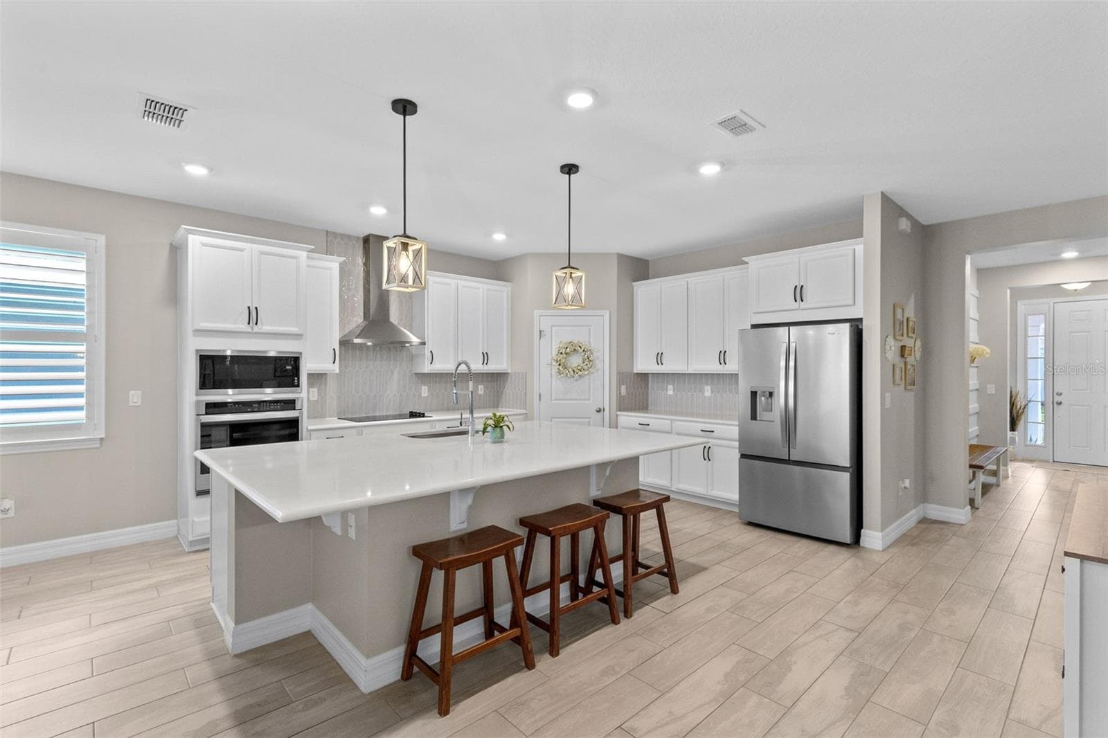Kitchen features a breakfast bar and quartz countertops, designer backsplash, pendant lighting, built in wall oven, microwave & vented range hood - 1274 SILO DR, ST CLOUD