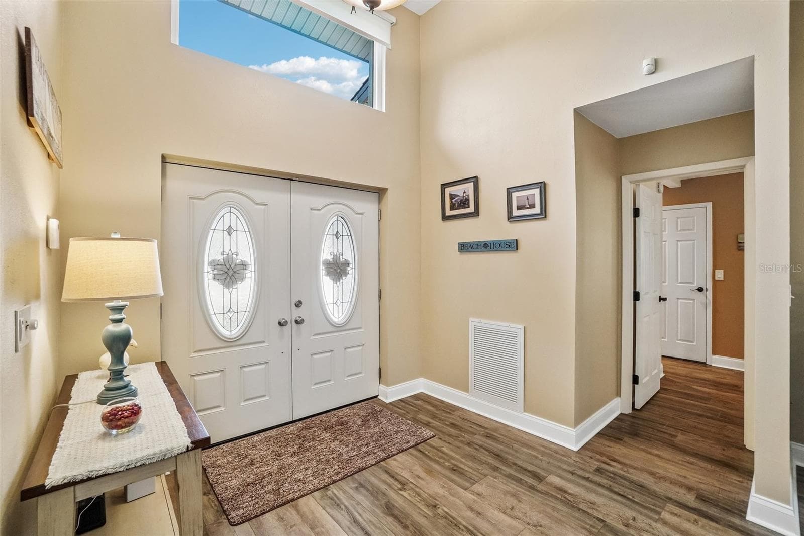 Foyer – Decorative double entry doors and a high transom window create a bright, welcoming arrival, complemented by wood-look flooring and easy access to the adjoining living spaces. - 971 CORTLAND WAY, PALM HARBOR