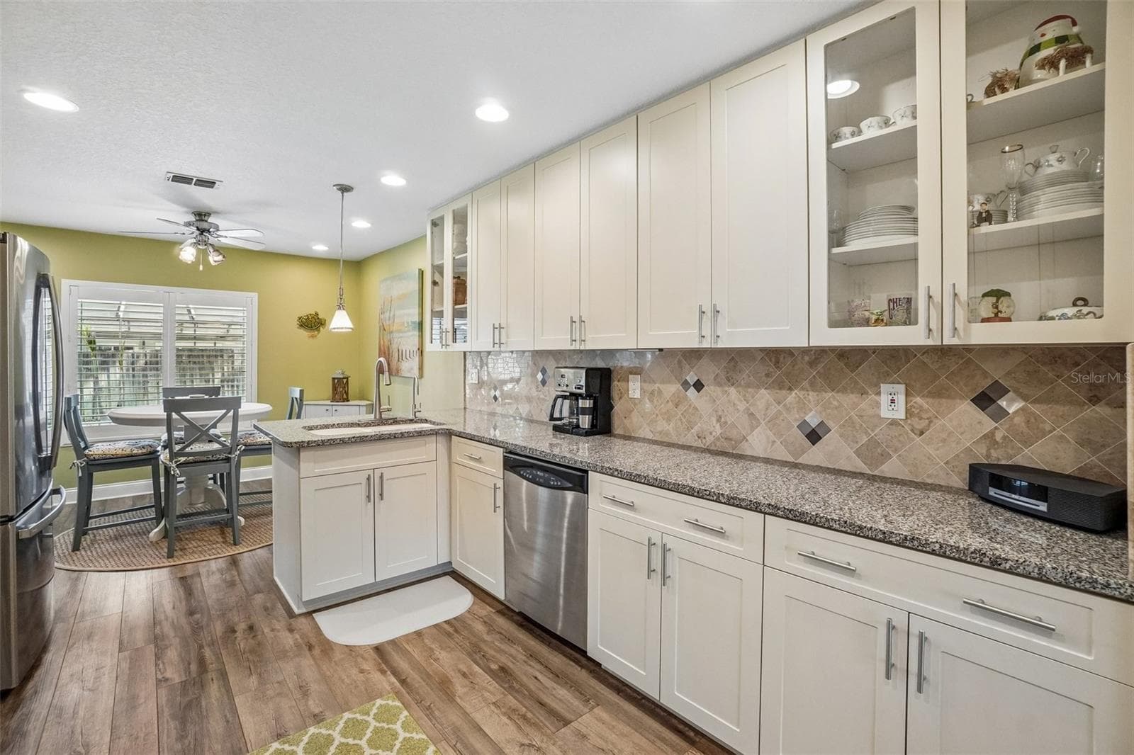 Kitchen – Another kitchen view highlights generous counter space, plentiful cabinetry including glass-front display cabinets, stainless steel appliances, and an open connection to the breakfast nook. - 971 CORTLAND WAY, PALM HARBOR