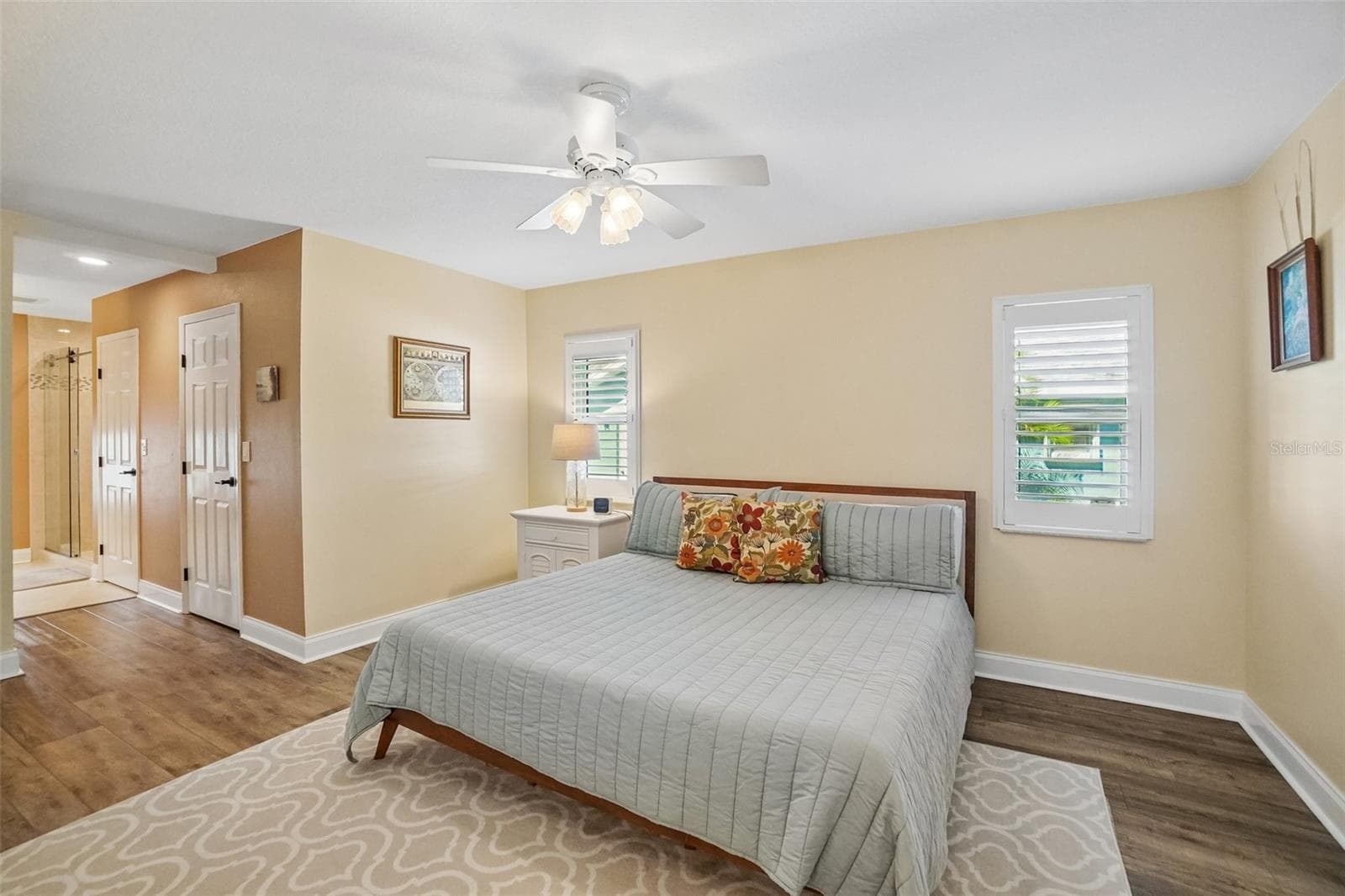 Primary Bedroom – Another view highlights the room’s generous proportions, dual shuttered windows, ceiling fan, and convenient access toward the adjoining bath and closet areas. - 971 CORTLAND WAY, PALM HARBOR