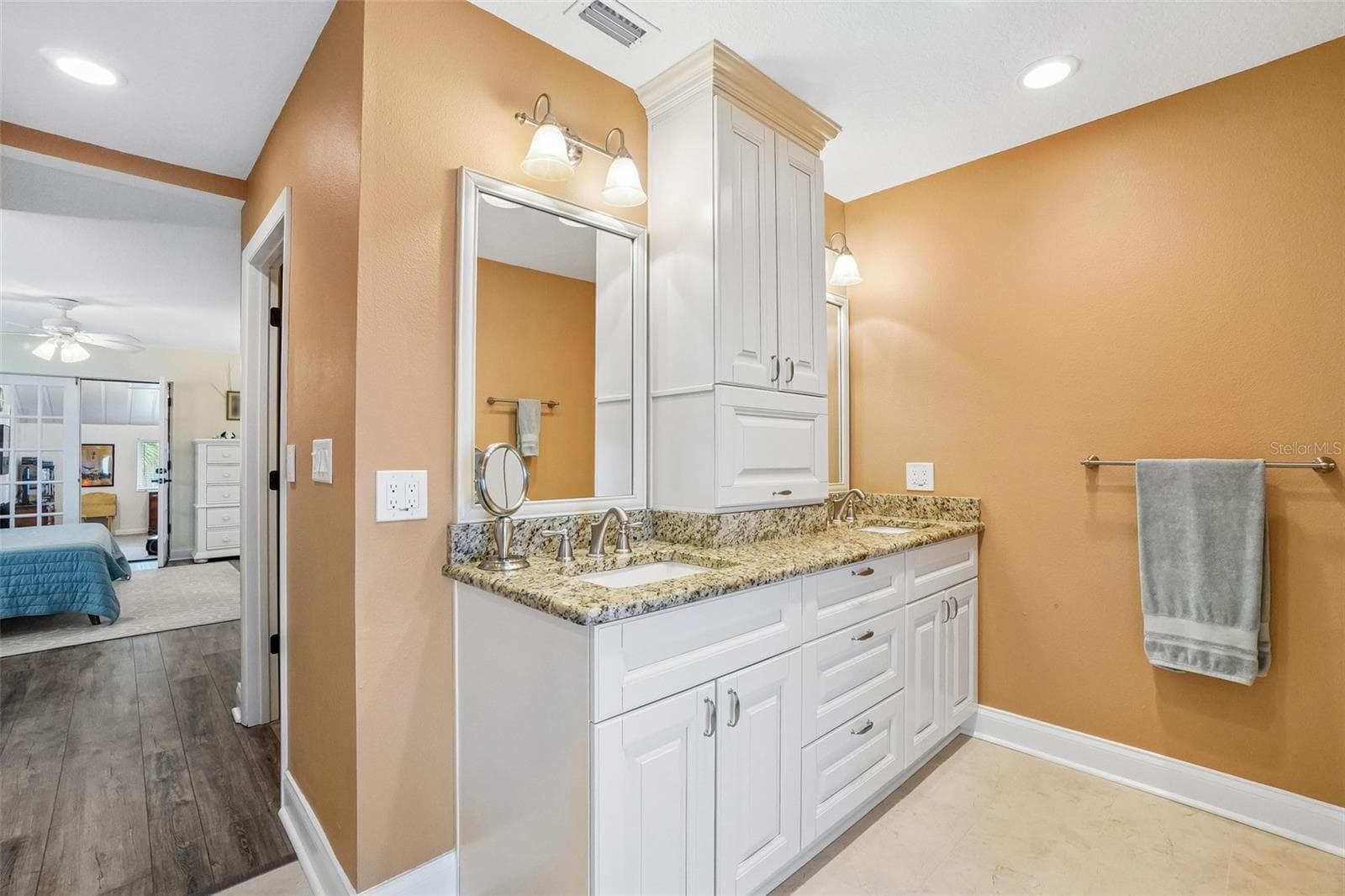 Primary Ensuite Bathroom – The primary ensuite features a spacious dual-sink vanity with granite countertops, abundant white cabinetry, a tall center storage cabinet, and bright vanity lighting. - 971 CORTLAND WAY, PALM HARBOR