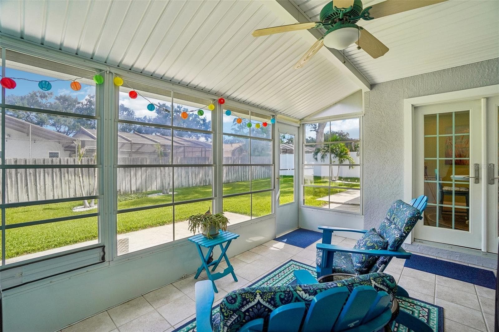 Enclosed Rear Patio – This light-filled enclosed patio features tiled flooring, a ceiling fan, expansive screened/windowed walls, and direct access to both the backyard and interior living spaces. - 971 CORTLAND WAY, PALM HARBOR