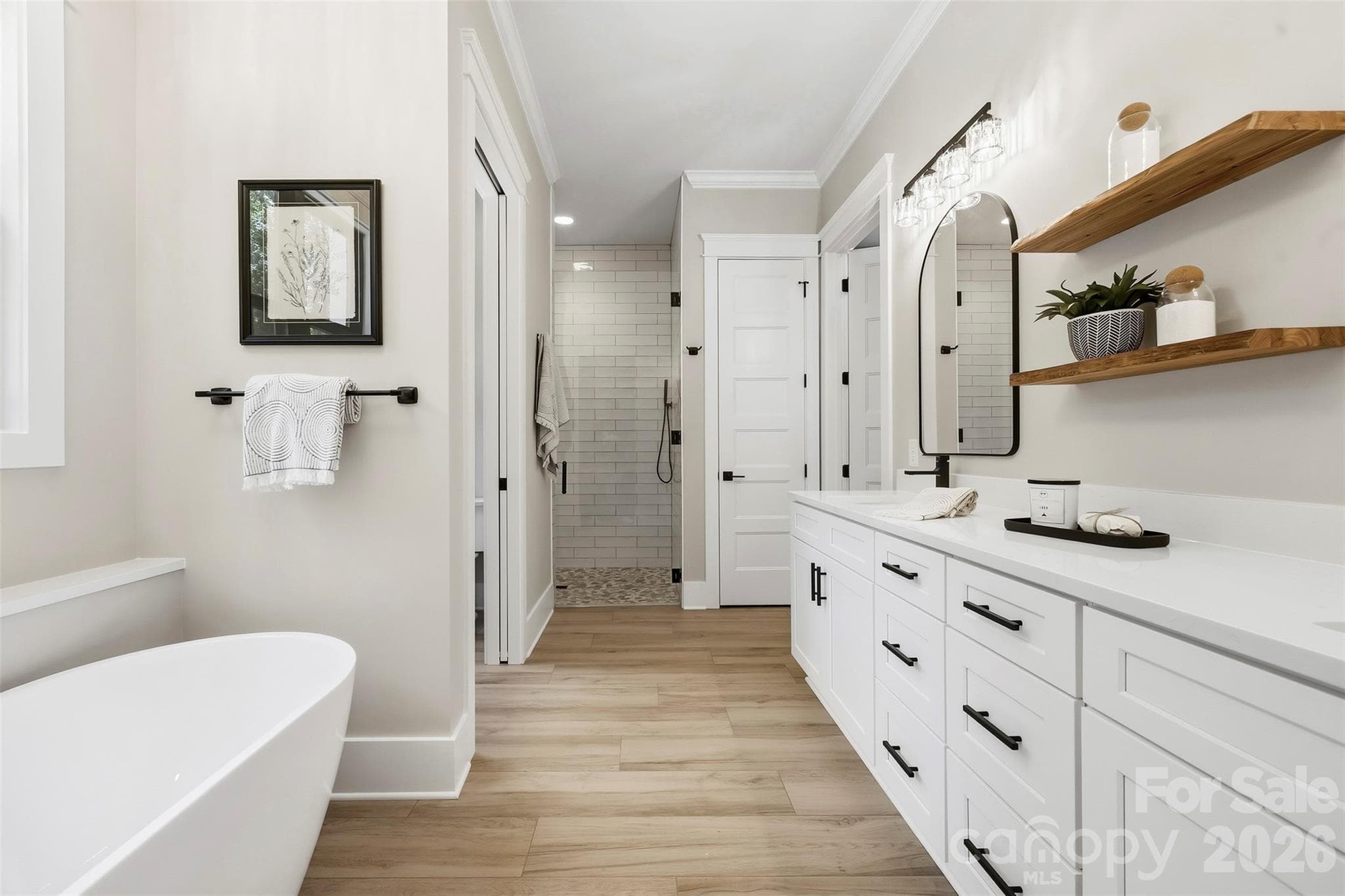 Primary bath with double vanity, free standing soaker tub, zero entry walk in shower, water closet, walk in closet, and linen closet. - 3515 Capricorn Road, Lancaster