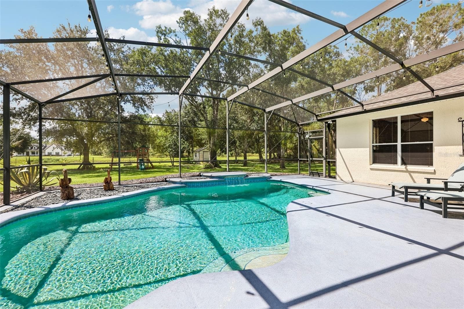 Step outside where the covered back patio and IN-GROUND POOL with WATERFALL FEATURE are enclosed within a screened lanai. - 19106 SHELDON ST, ORLANDO