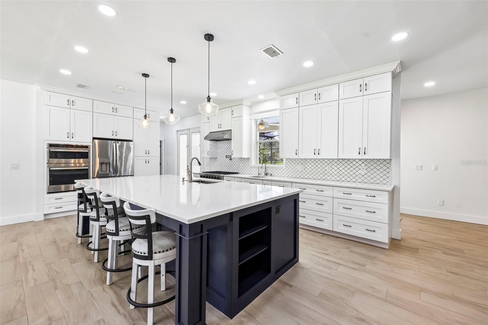 The Kitchen features an abundance of WHITE CABINETRY with UNDER-CABINET LED LIGHTING, a sleek backsplash, STAINLESS STEEL APPLIANCES and a generous island with BREAKFAST BAR seating. - 19106 SHELDON ST, ORLANDO