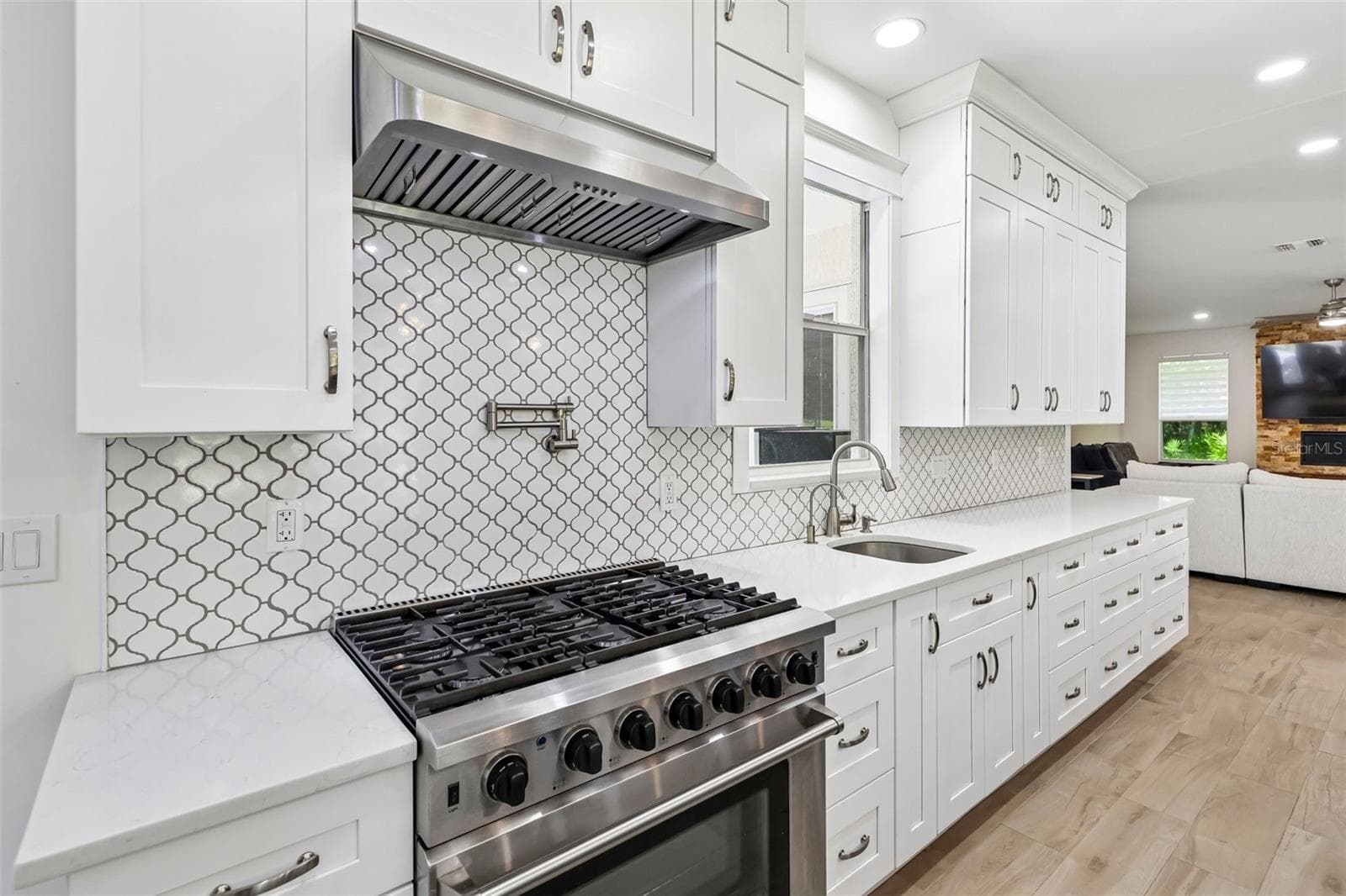 The Kitchen features an abundance of WHITE CABINETRY with UNDER-CABINET LED LIGHTING, a sleek backsplash, STAINLESS STEEL APPLIANCES and a generous island with BREAKFAST BAR seating. - 19106 SHELDON ST, ORLANDO