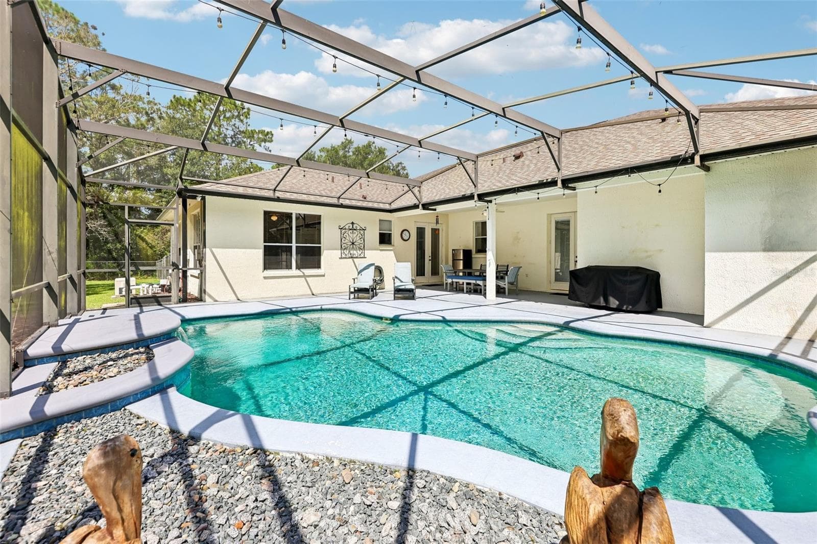 Step outside where the covered back patio and IN-GROUND POOL with WATERFALL FEATURE are enclosed within a screened lanai. - 19106 SHELDON ST, ORLANDO