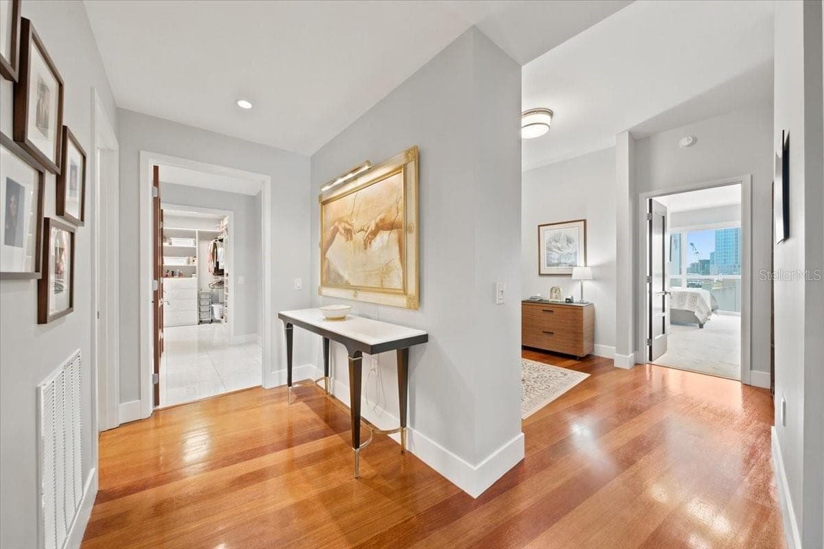Welcoming entry hallway with warm hardwood floors, high ceilings, gallery-style wall space, and seamless connections to the primary living suites and guest areas. - 111 N 12TH ST #1704, TAMPA