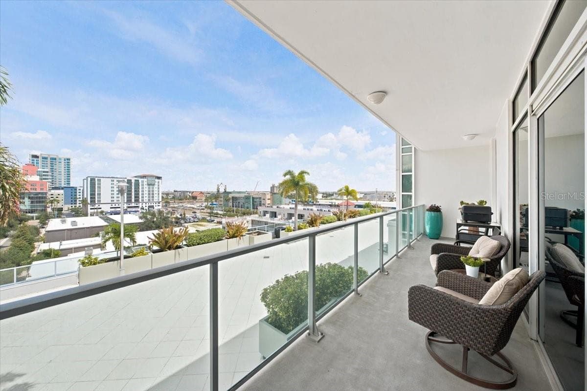 Spacious covered balcony with glass railing, offering comfortable outdoor seating and open views of the surrounding cityscape. - 111 N 12TH ST #1704, TAMPA